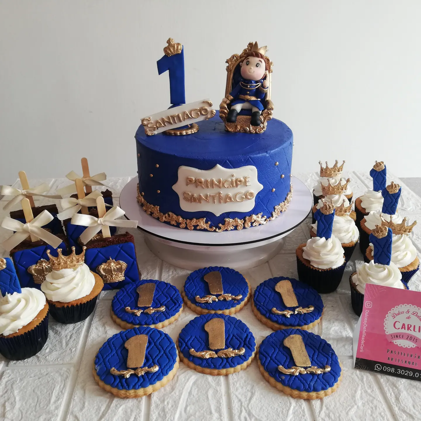 Pastel azul de primer cumpleaños con cupcakes y galletas