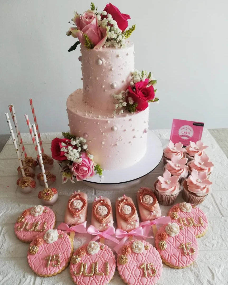 Pastel rosa de tres niveles con flores, cupcakes y cake pops