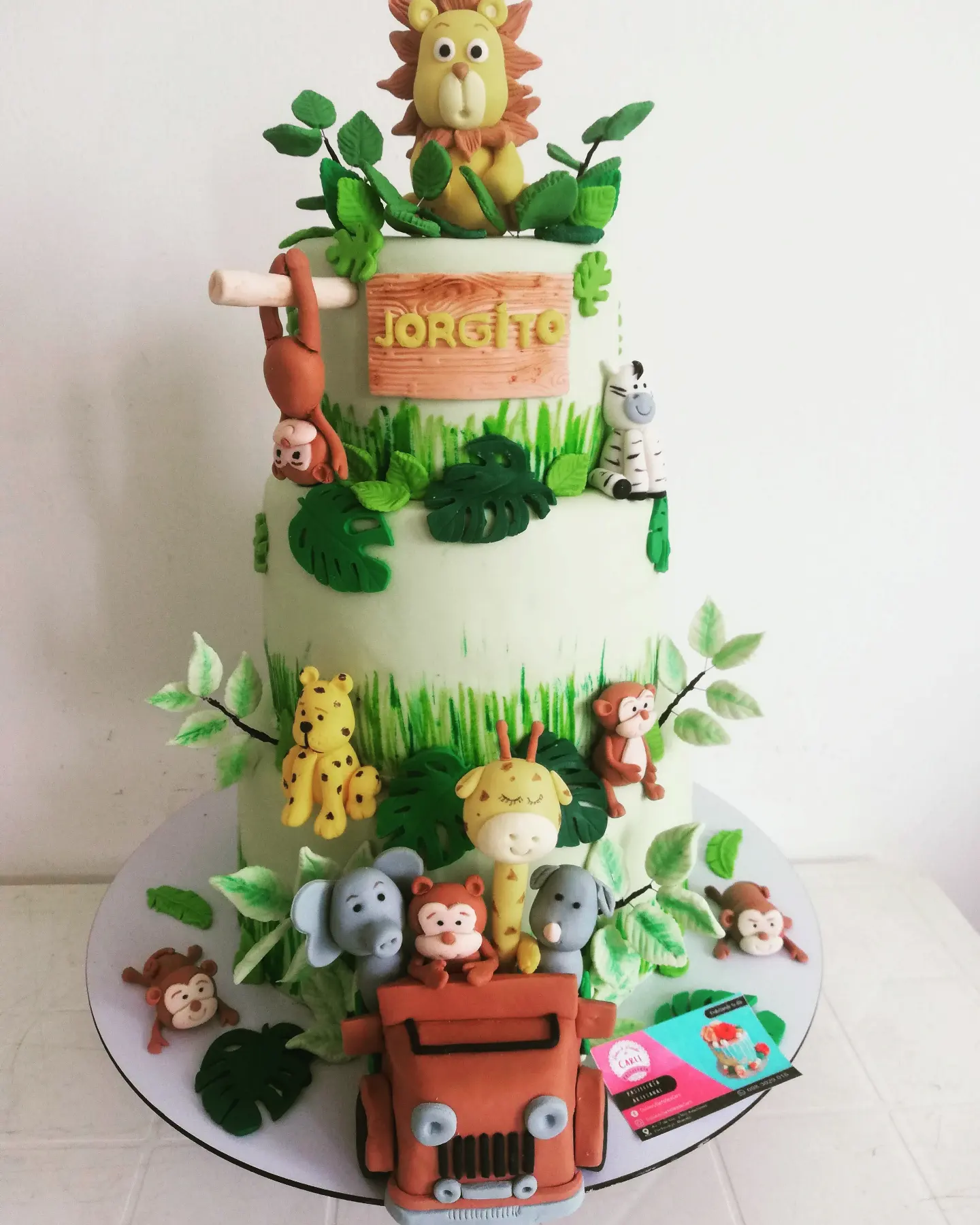 Pastel de dos niveles con animales de la selva y jeep