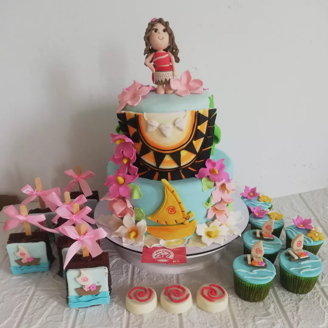 Mesa dulce de Moana con pastel, cupcakes y galletas